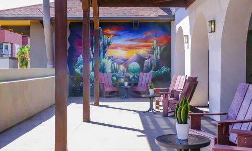 a patio with chairs and a painting on the wall
