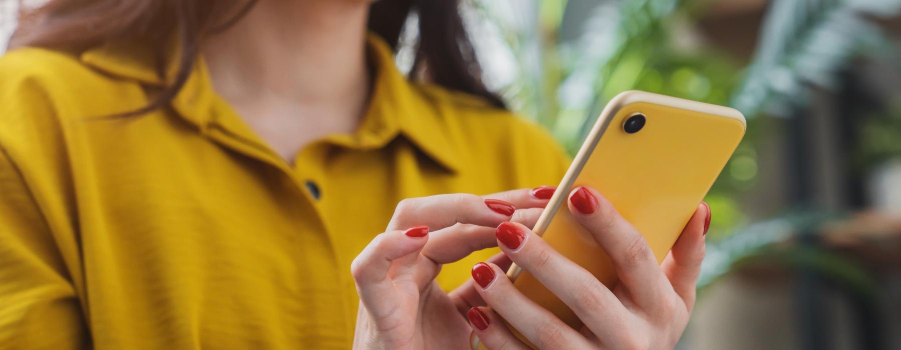 a woman holding a yellow cell phone