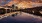 sunset over body of water near bridge